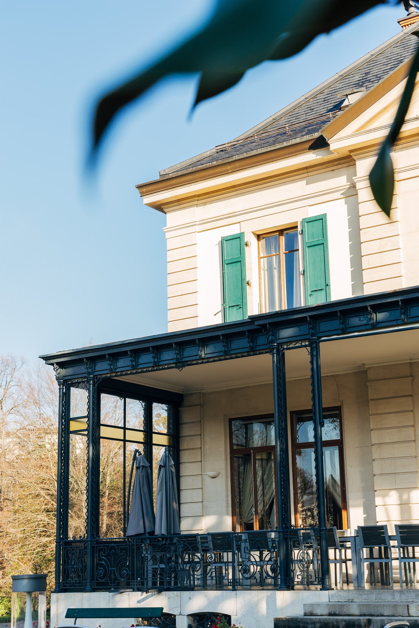 Façade avec volets verts et véranda en fer forgé